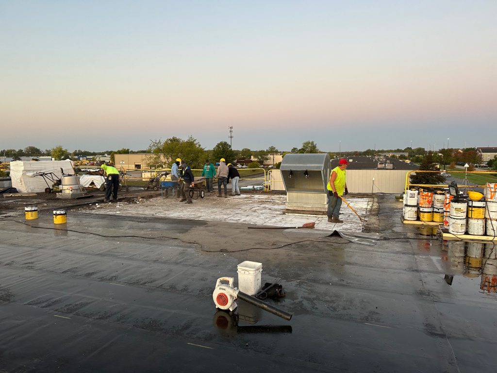group workers atop a roof applying seal coating